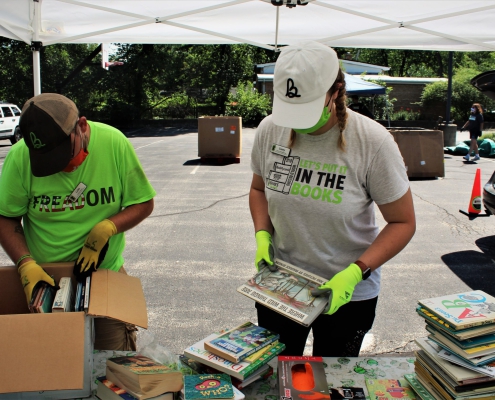 volunteers sort books under an outdoor tent