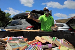 a volunteer sorts books into a massive bin