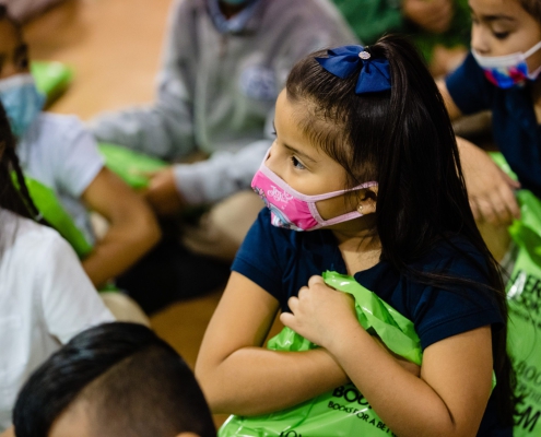 schoolchildren wear face masks and clutch green Bernie's Book Bank bags