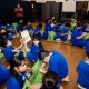 children sit on the floor and look through the books in their green Bernie's Book Bank bags
