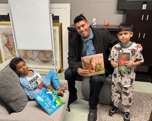 Officer Magellon with two boys holding Spanish-language books