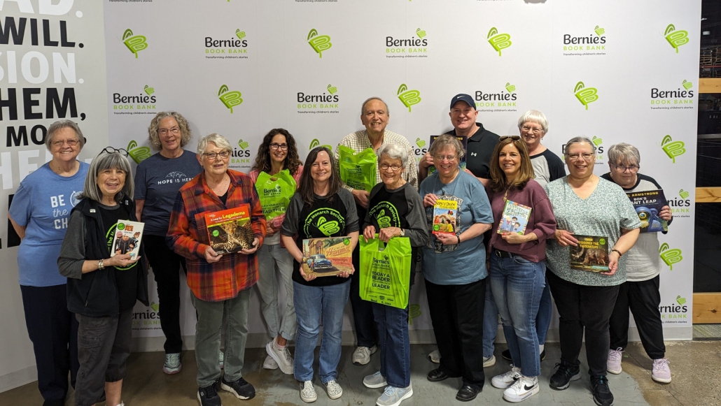 fourteen volunteers from Bernie's Book Bank 50 hour club pose and smile