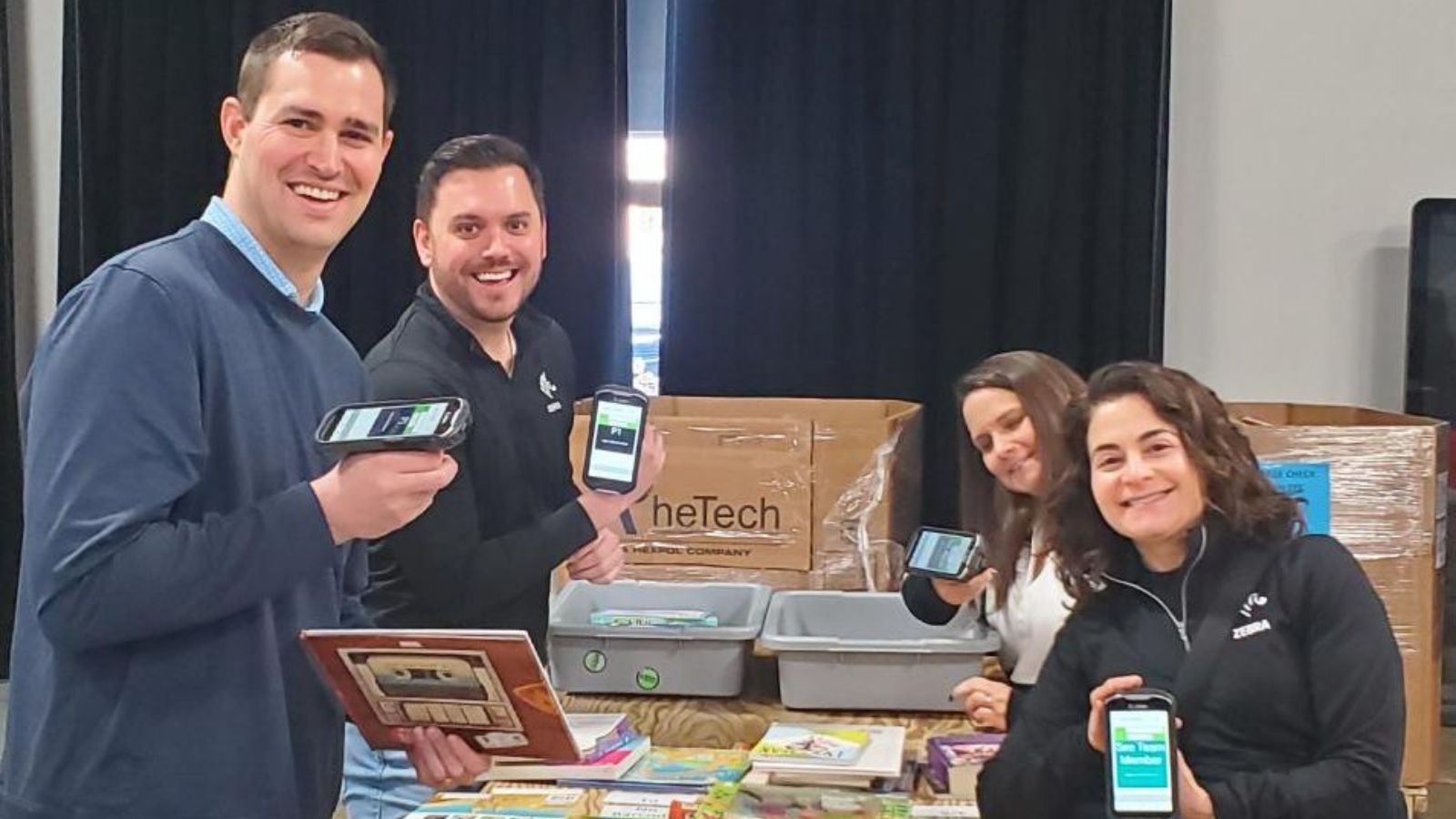 four employees of Zebra Technologies smile and volunteer for Bernie's Book Bank