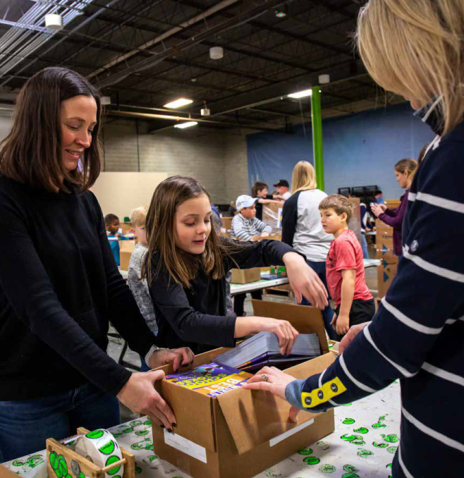 three volunteers happily open boxes of donated books