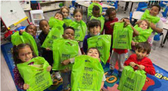 children happily hold up green Bernie's Book Bank bags