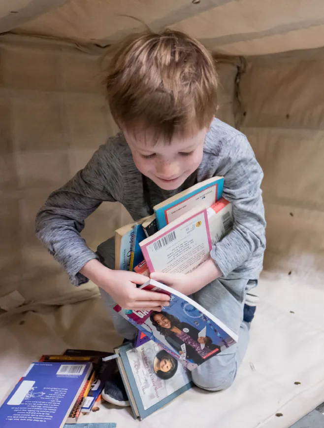 a kid clutches a pile of chapter books and smiles