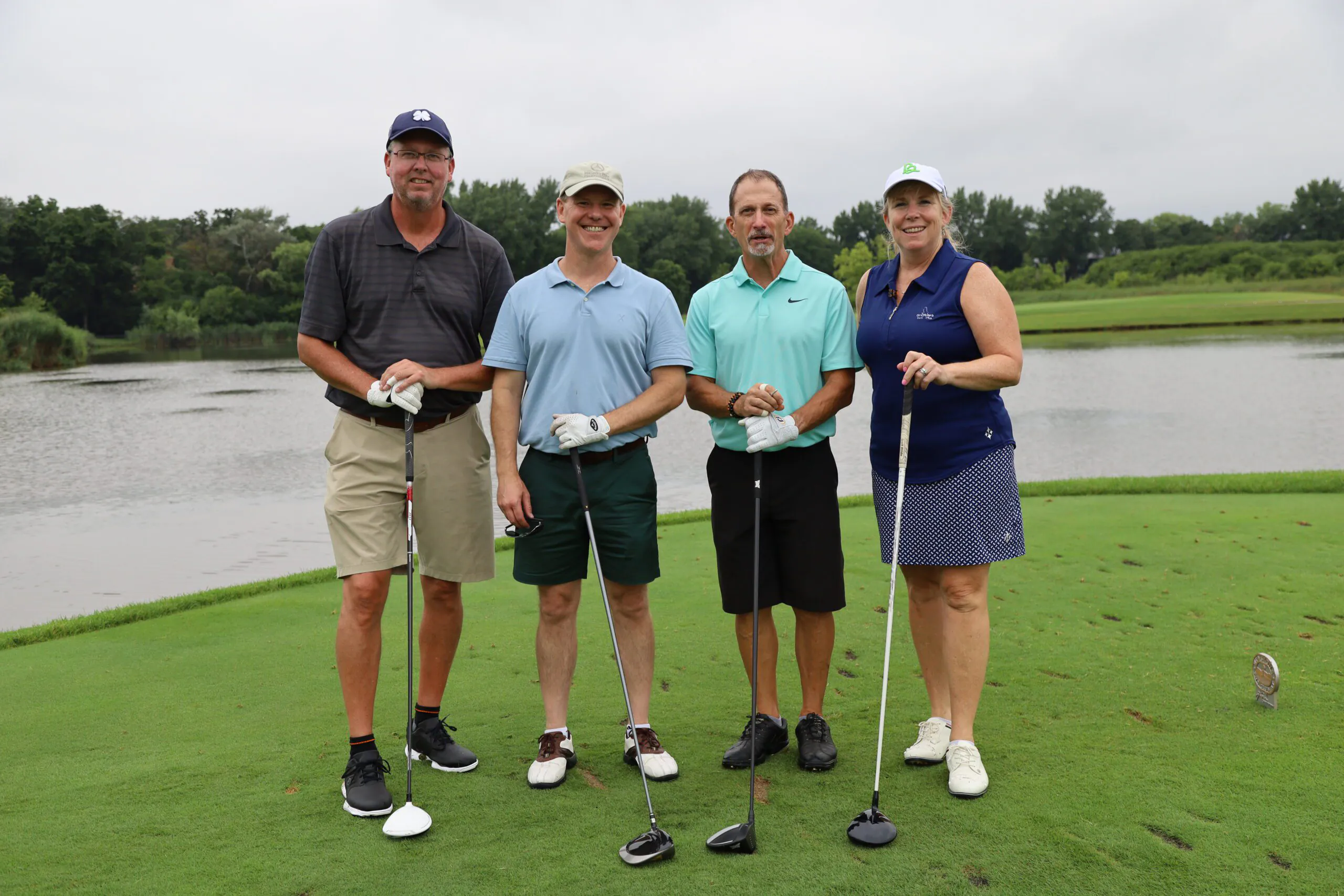 four golfers at a Bernie's Books event pose on the green