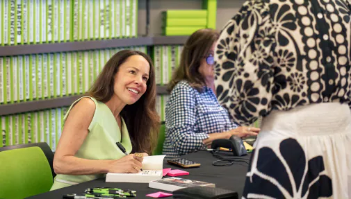 an author signs a book and smiles