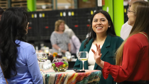 three women smile and chat at a high-top table