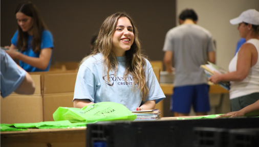 a volunteer packs books and smiles