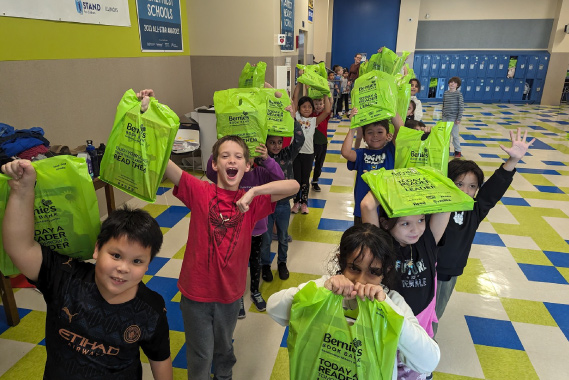 schoolchildren shout with joy and proudly hold up their Bernie's book bags