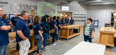 blue-shirted volunteers from Abbvie receive orientation before sorting books at Bernie's Book Bank