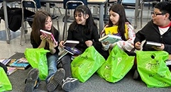 Schoolchildren happily look through their green bags of donated books