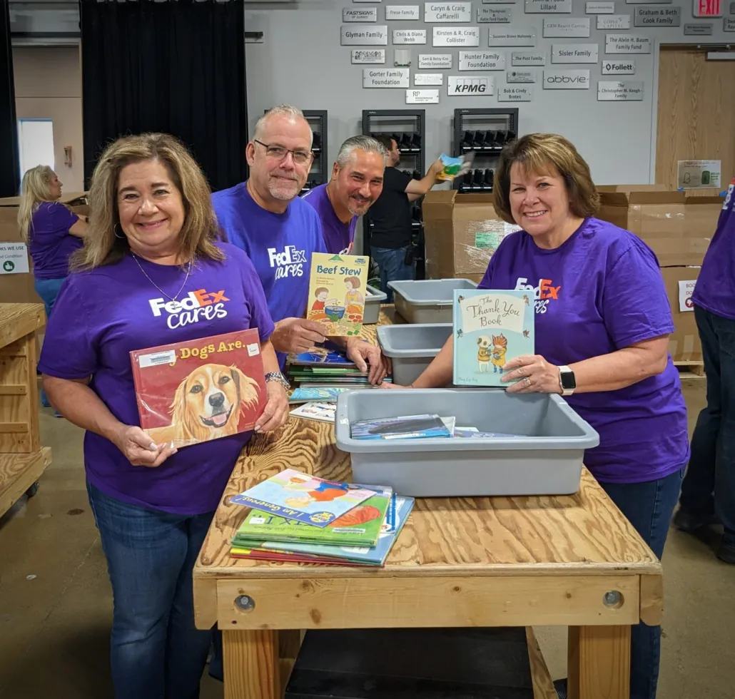 Four purple-shirted volunteers from FedEx sort books