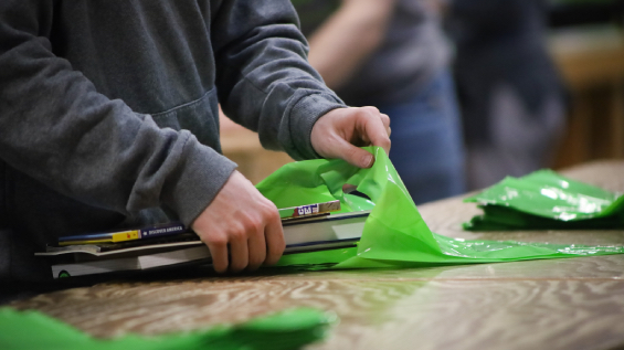 close-up on hands packing books into a green Bernie's Books bag