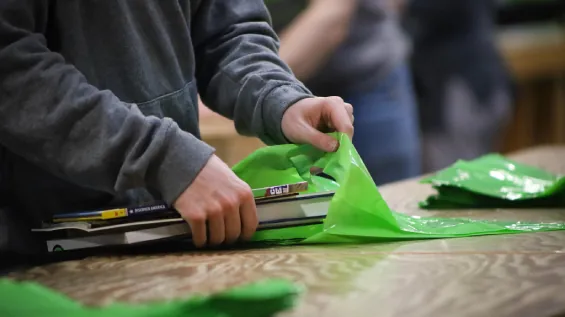 close-up on hands packing books into a green Bernie's Books bag