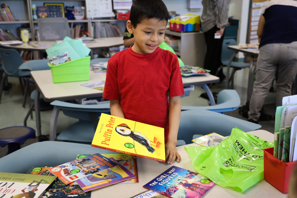 a schoolchild smiles and holds a large picture book about puffins