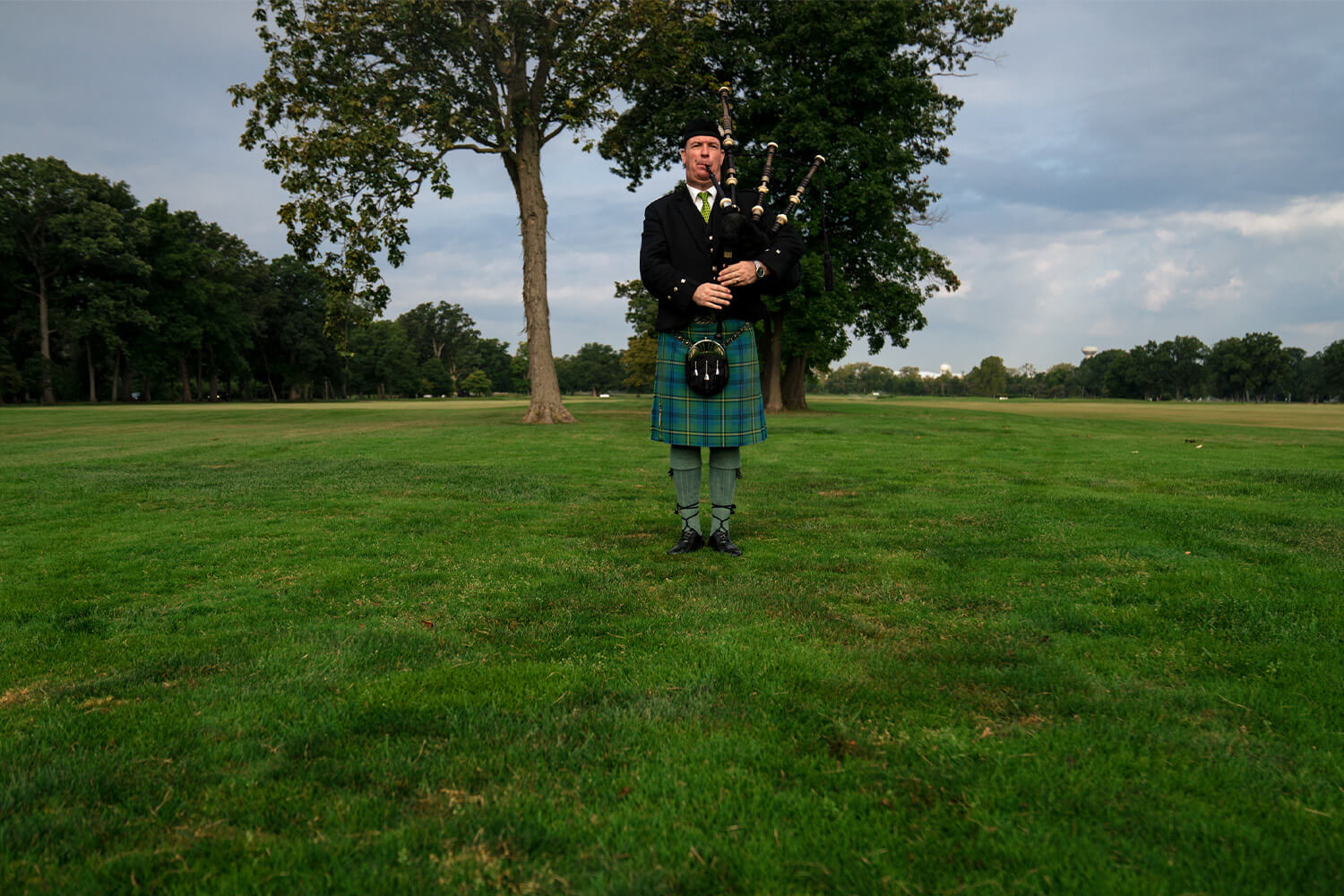 An Individual in traditional Scottish atire playing the bag pipes at a golf event