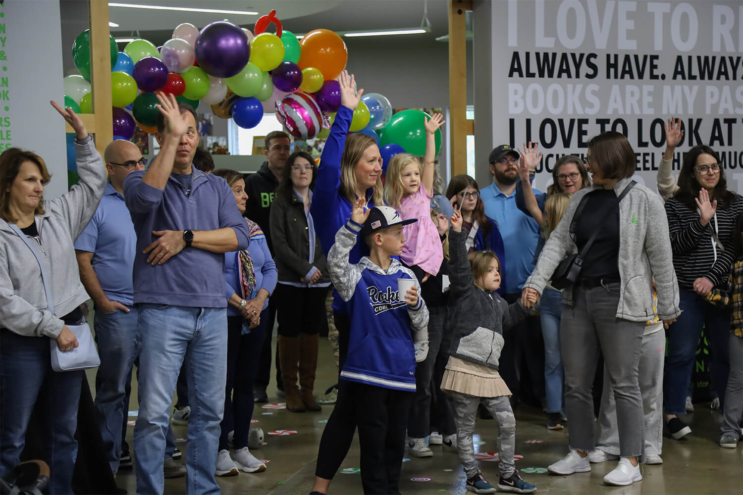 a group of people raising their hands at a book giving event