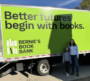 Elsie and her mom posing in front of the Bernie's Book Bank truck