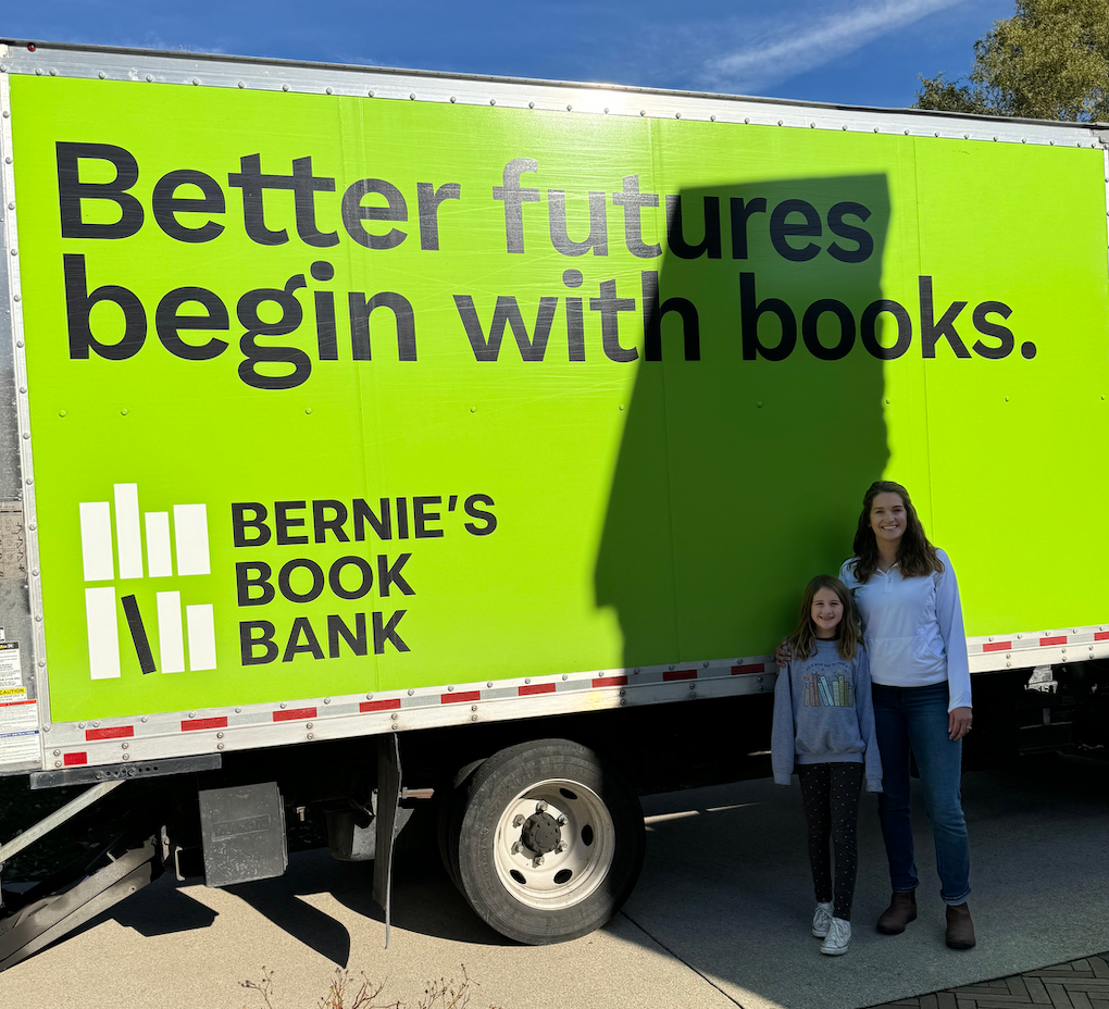 Elsie and her mom posing in front of the Bernie's Book Bank truck