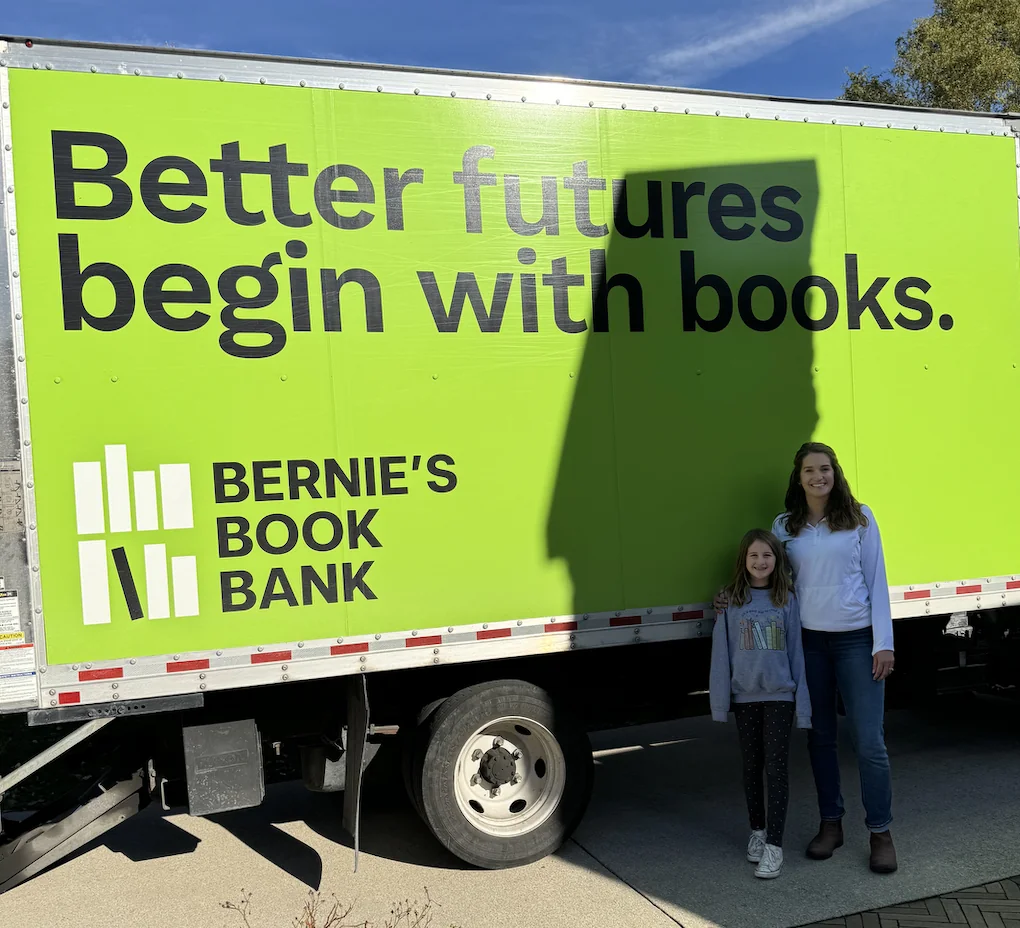 Elsie and her mom posing in front of the Bernie's Book Bank truck